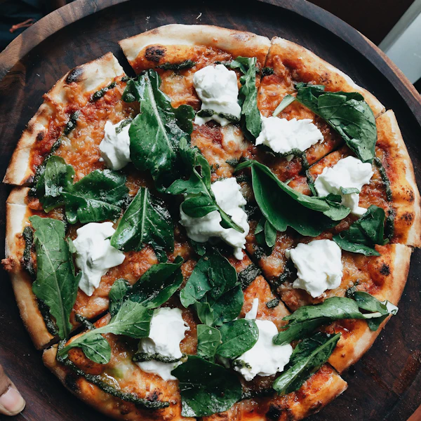 A pizza topped with greens and soft cheese