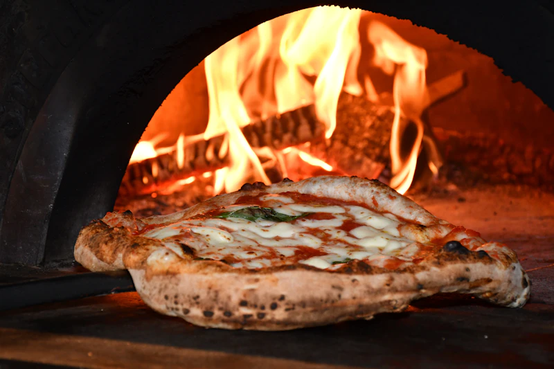 A pizza baking in a wood-fired oven