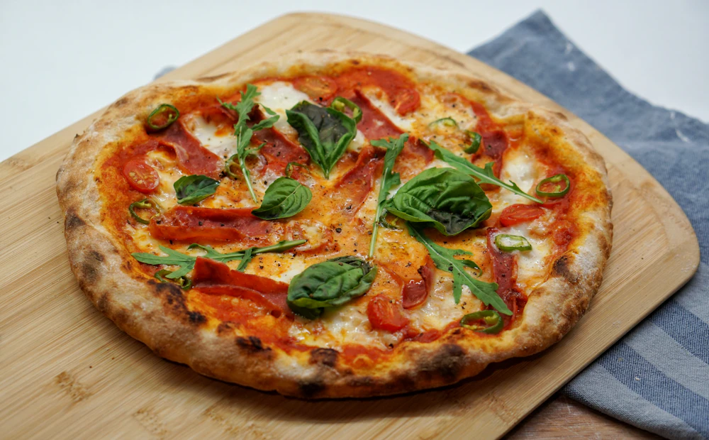 A pizza with basil on a wooden board