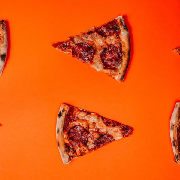 Two slices of pizza on an orange table