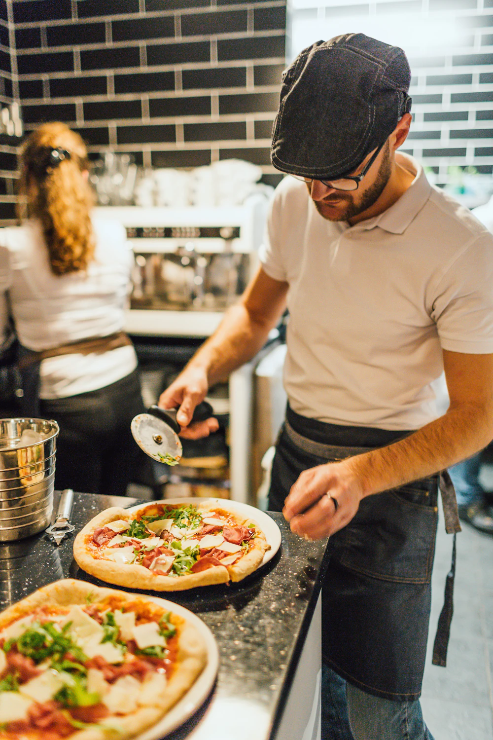 A pizza maker slicing a fresh pizza in the kitchen